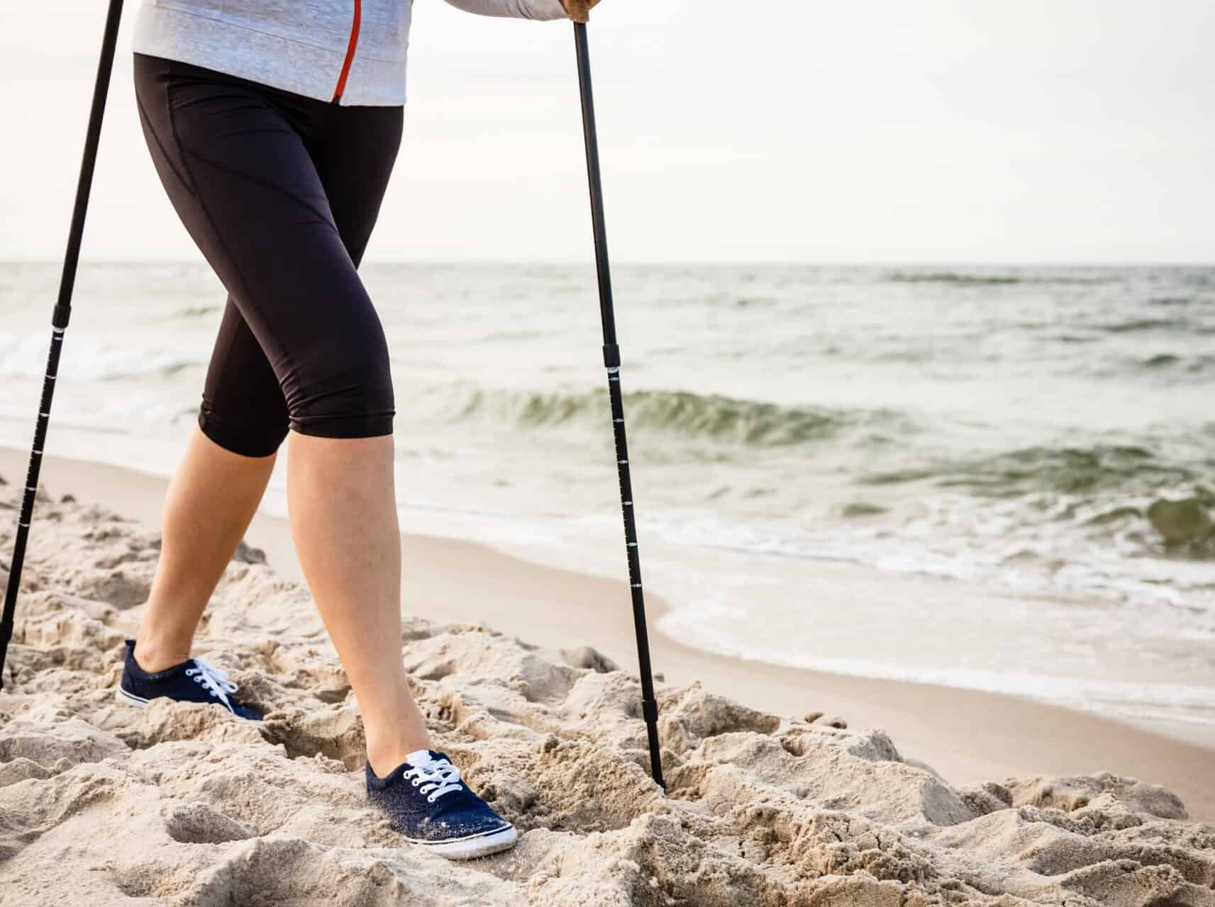 Nordic walking – young woman working out on beach