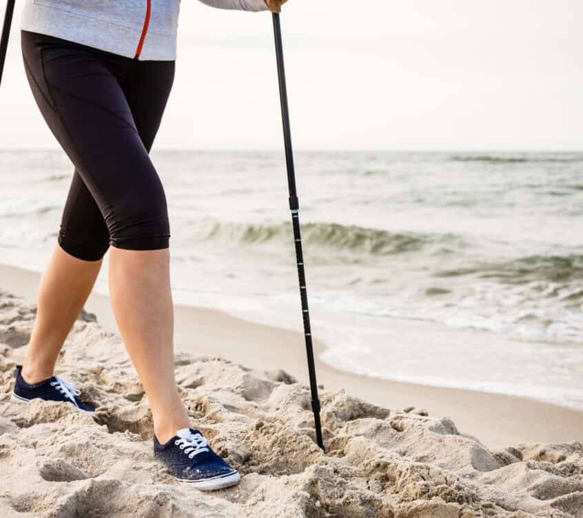 Nordic walking – young woman working out on beach