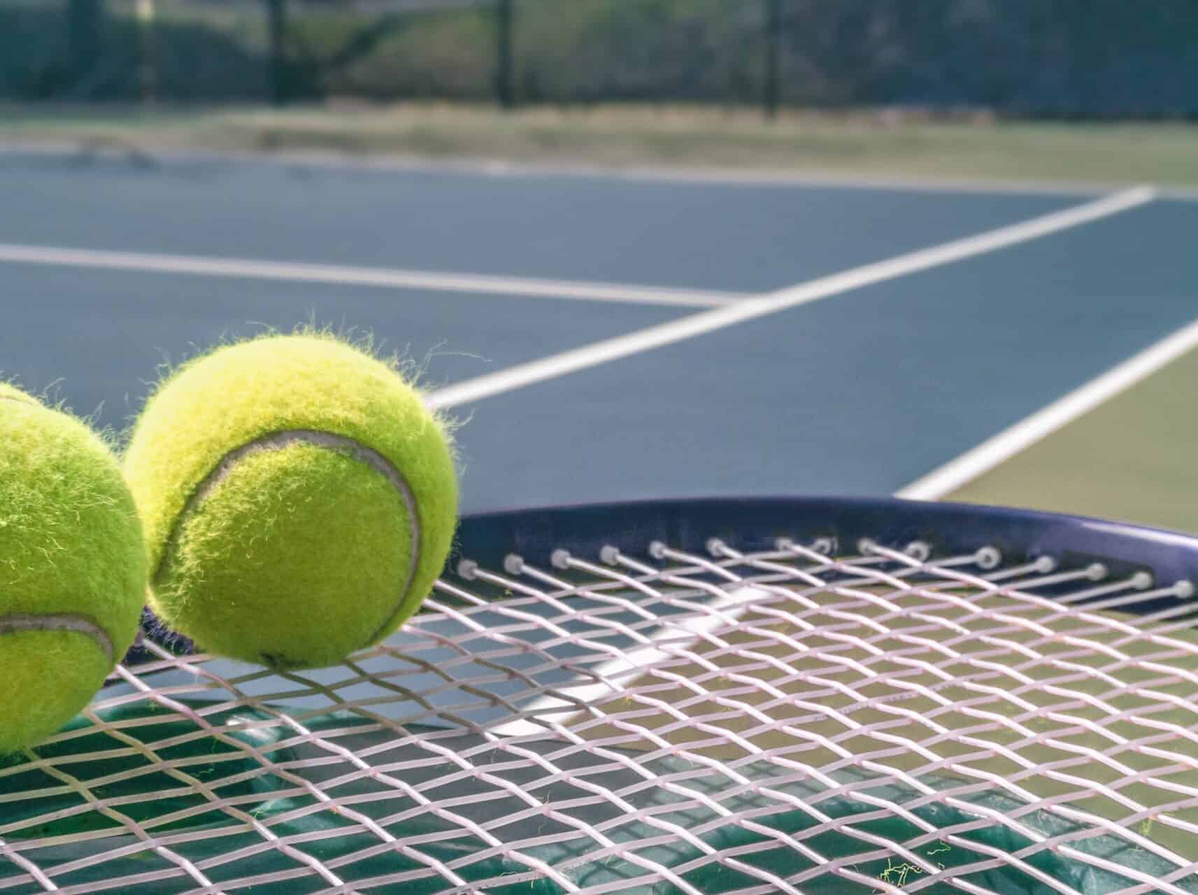 Tennis court panorama background with blue racket and two tennis balls ready to play match on outdoor courts summer sport lifestyle. Mobile photo picture.