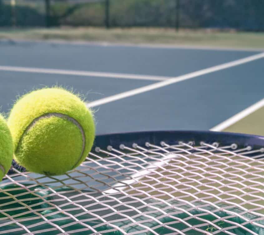 Tennis court panorama background with blue racket and two tennis balls ready to play match on outdoor courts summer sport lifestyle. Mobile photo picture.